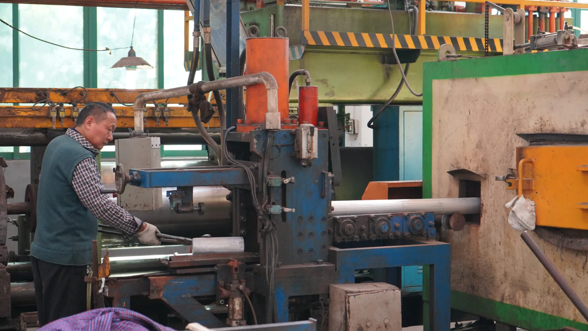 Operator guiding a freshly extruded aluminium profile out of the press