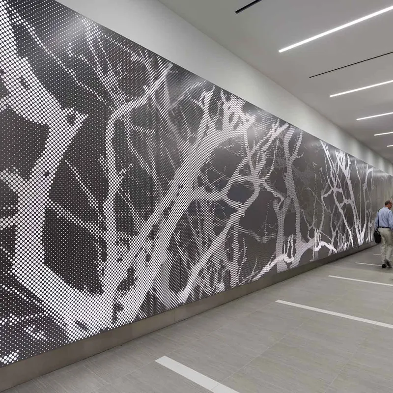 Long perforated aluminium wall panel with a tree-branch image in a passageway